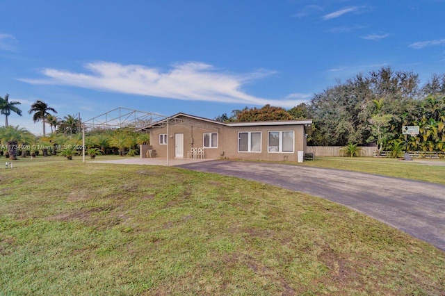 view of front of property featuring driveway, a front lawn, and fence