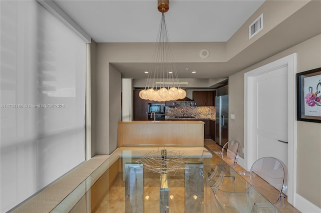 kitchen featuring high end fridge, decorative backsplash, and wall chimney range hood