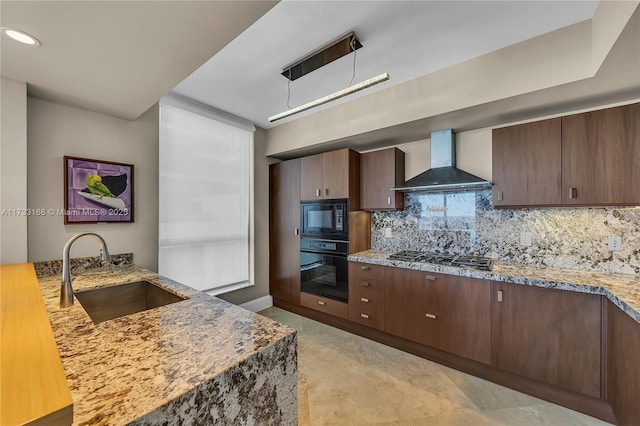 kitchen featuring wall chimney exhaust hood, sink, pendant lighting, light stone countertops, and black appliances