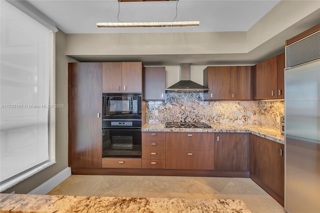 kitchen featuring tasteful backsplash, light stone countertops, wall chimney range hood, and black appliances