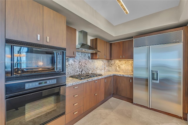 kitchen featuring backsplash, wall chimney exhaust hood, light stone countertops, and black appliances