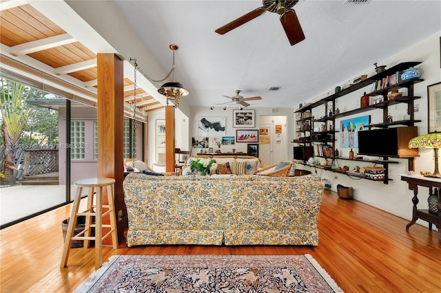 living room featuring ceiling fan, hardwood / wood-style flooring, and beamed ceiling