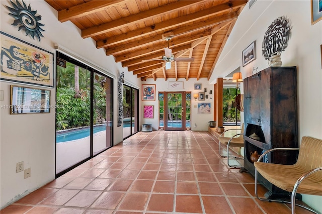 unfurnished sunroom with a fireplace, vaulted ceiling with beams, ceiling fan, wooden ceiling, and french doors