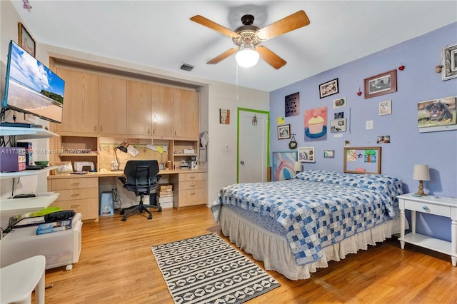 bedroom with built in desk, light hardwood / wood-style floors, and ceiling fan