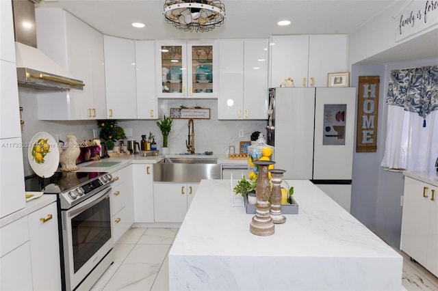 kitchen featuring wall chimney exhaust hood, sink, a kitchen island, electric stove, and white cabinets