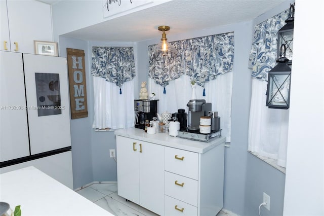 interior space with white cabinetry, white refrigerator, decorative light fixtures, and a textured ceiling