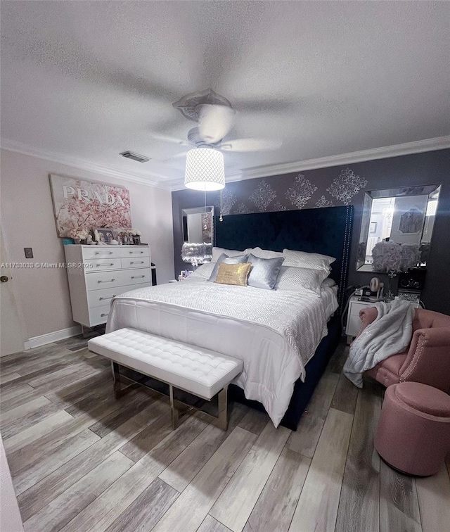 bedroom featuring a textured ceiling, wood-type flooring, ornamental molding, and ceiling fan