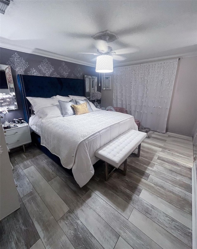 bedroom featuring ornamental molding, hardwood / wood-style floors, a textured ceiling, and ceiling fan