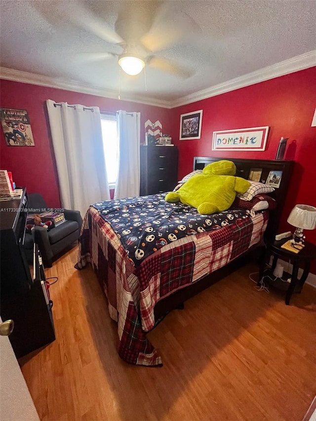 bedroom featuring ornamental molding, wood-type flooring, a textured ceiling, and ceiling fan