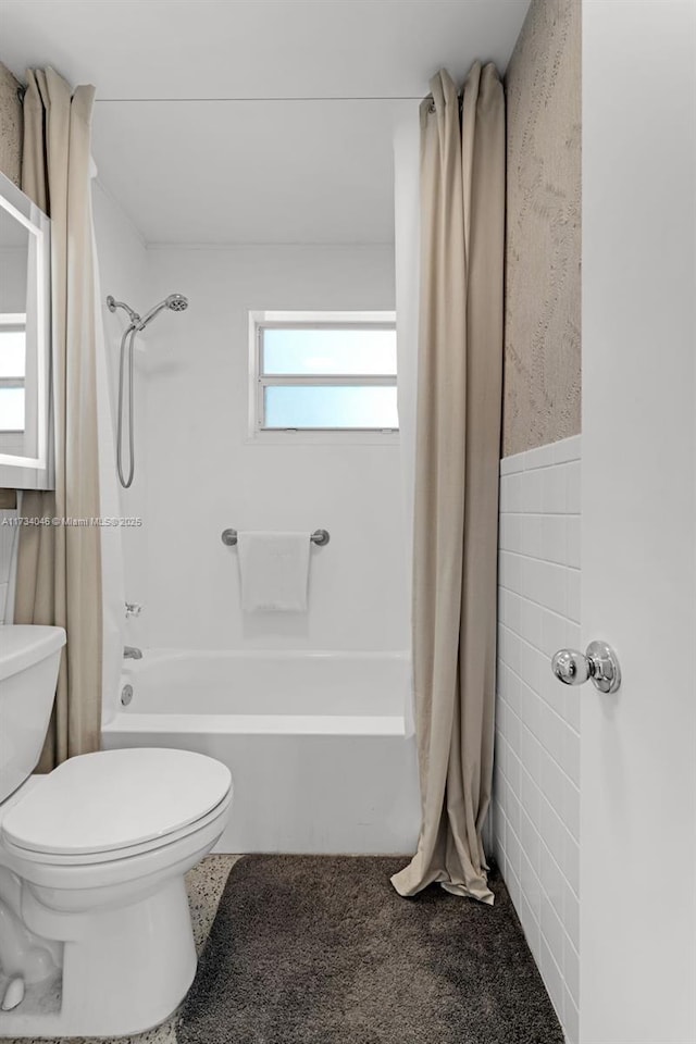 bathroom with shower / bath combo, tile walls, and toilet