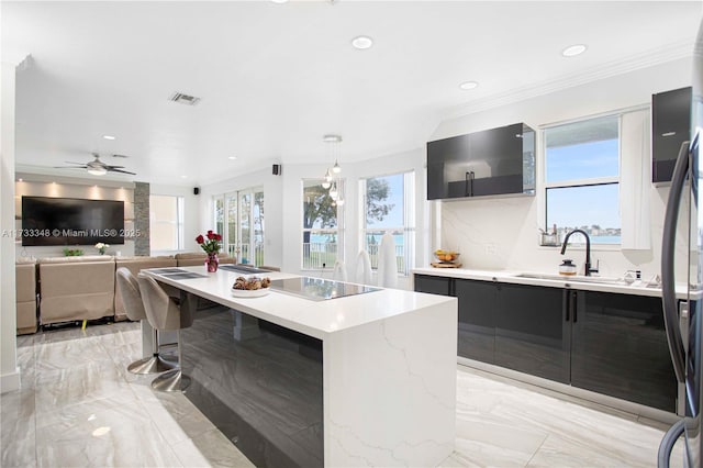 kitchen with a kitchen island, pendant lighting, tasteful backsplash, sink, and black electric cooktop