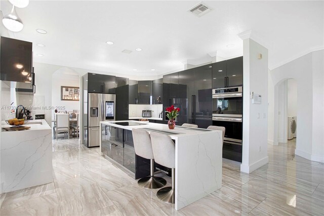 kitchen with pendant lighting, stainless steel fridge, a kitchen breakfast bar, a water view, and wall chimney range hood