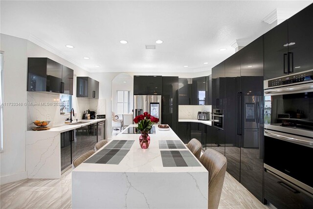 kitchen with appliances with stainless steel finishes, washer / clothes dryer, gray cabinetry, a kitchen breakfast bar, and a center island