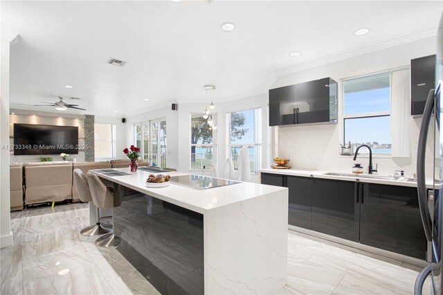 kitchen featuring sink, a breakfast bar, appliances with stainless steel finishes, a center island, and light stone countertops