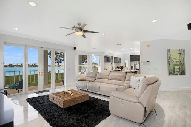 living room with ceiling fan and a water view