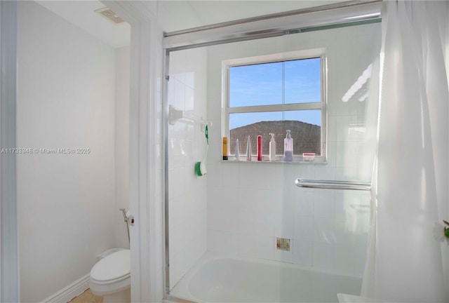 bathroom with bath / shower combo with glass door and toilet