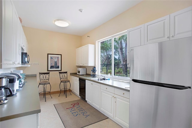 kitchen featuring white cabinetry, sink, light tile patterned floors, and black appliances