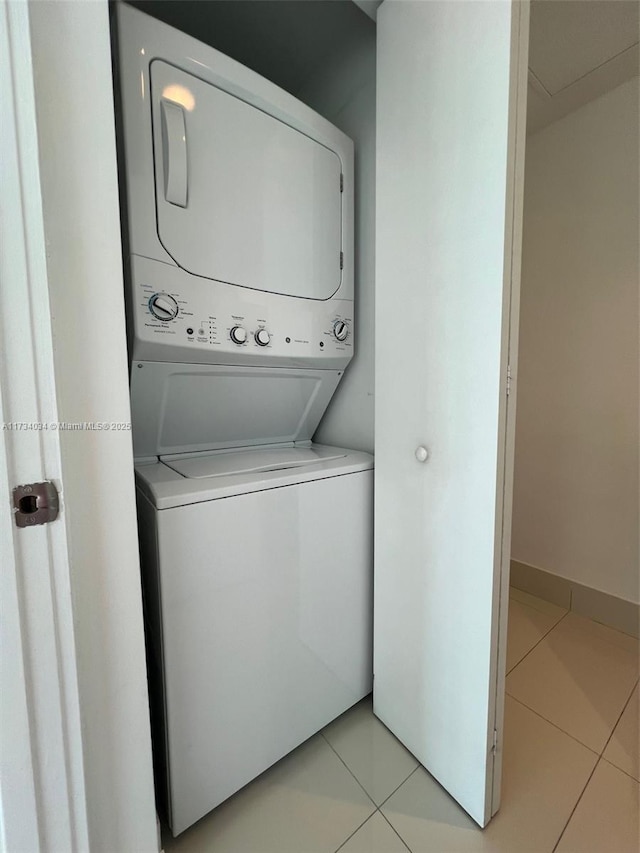 laundry room with light tile patterned flooring and stacked washer / dryer