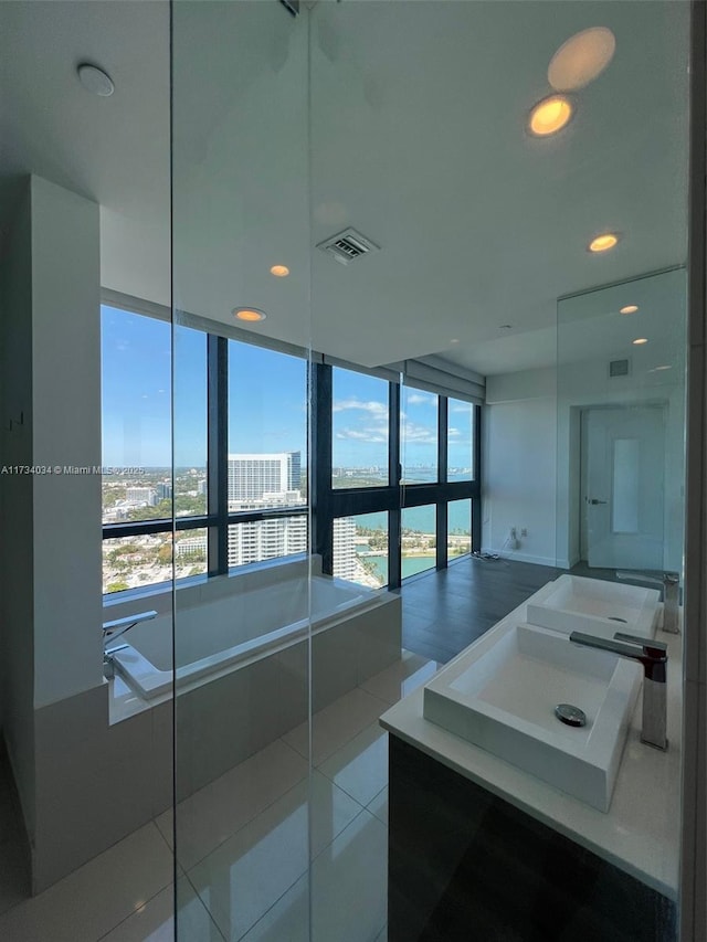 bathroom featuring tile patterned flooring, sink, and tiled bath