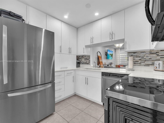 kitchen with white cabinetry, light tile patterned floors, tasteful backsplash, and stainless steel refrigerator