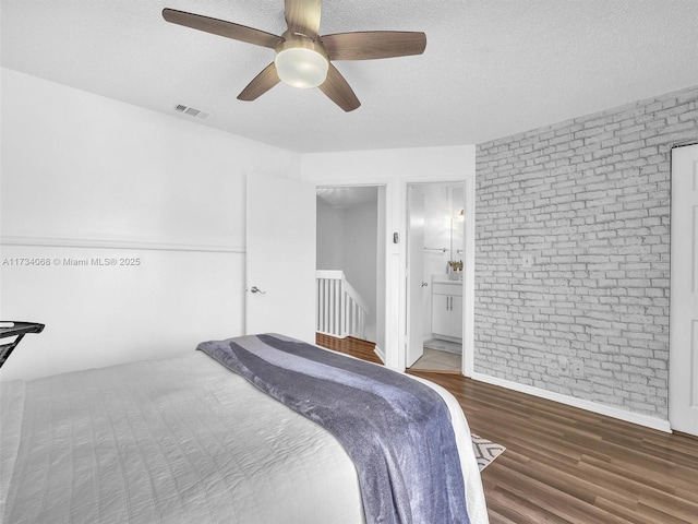 bedroom featuring ceiling fan, ensuite bathroom, dark hardwood / wood-style floors, and a textured ceiling