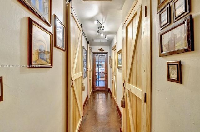 corridor featuring track lighting and concrete flooring