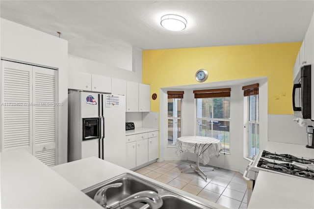 kitchen featuring light tile patterned floors, white appliances, and white cabinets