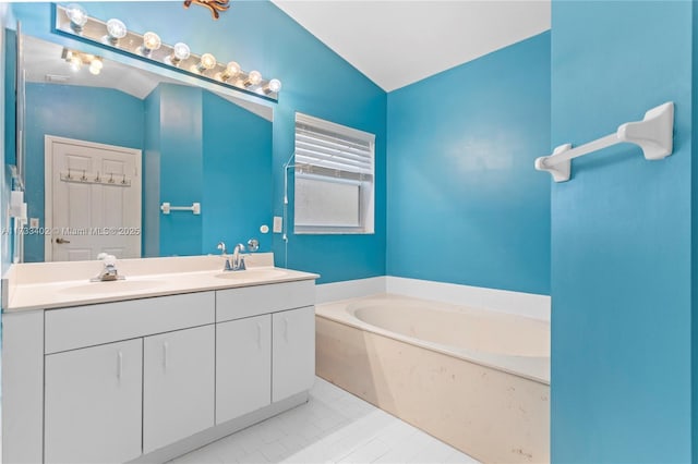 bathroom featuring tile patterned floors, vanity, a bathing tub, and vaulted ceiling