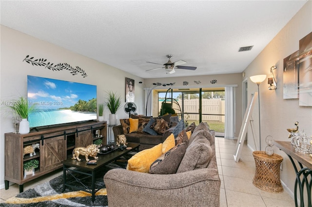 living room with ceiling fan, light tile patterned floors, and a textured ceiling