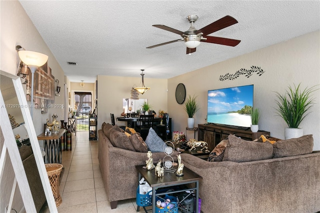 living room featuring ceiling fan, a textured ceiling, and light tile patterned flooring