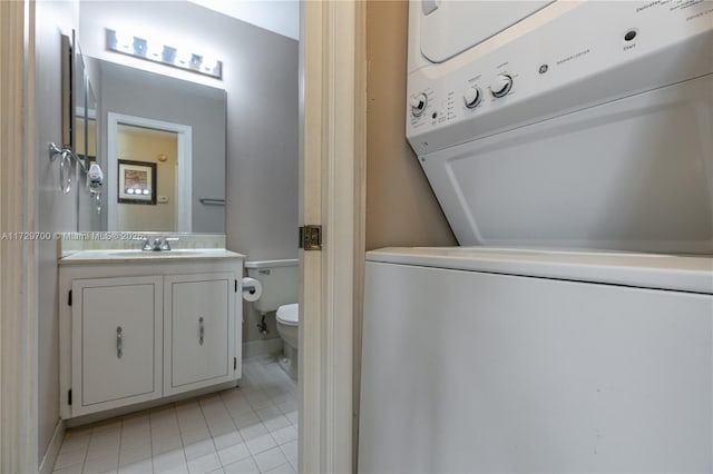 bathroom with vanity, stacked washer and clothes dryer, tile patterned floors, and toilet