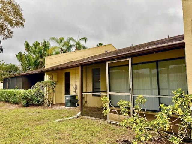 view of side of home featuring cooling unit and a lawn