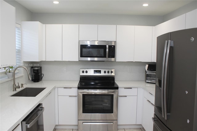 kitchen featuring white cabinetry, sink, backsplash, and appliances with stainless steel finishes