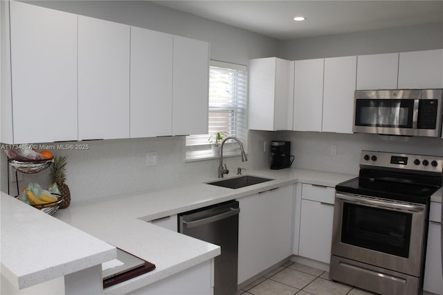 kitchen with appliances with stainless steel finishes, sink, white cabinets, backsplash, and kitchen peninsula