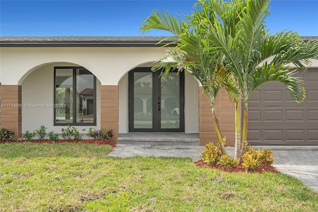 property entrance with an attached garage, a shingled roof, a yard, french doors, and stucco siding