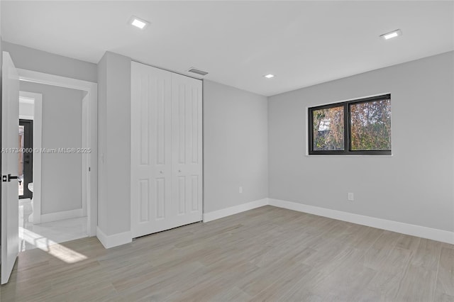 unfurnished bedroom featuring a closet, baseboards, visible vents, and light wood finished floors