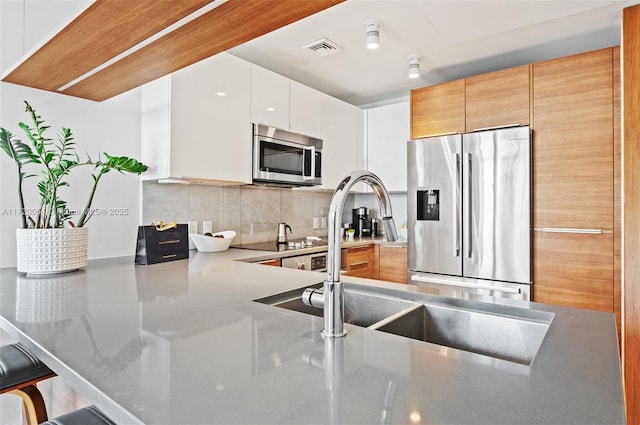 kitchen featuring tasteful backsplash, white cabinetry, sink, a kitchen breakfast bar, and stainless steel appliances