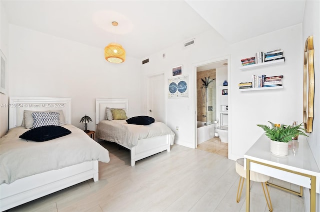 bedroom featuring connected bathroom and light hardwood / wood-style floors