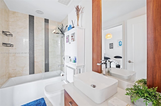 full bathroom with vanity, tiled shower / bath, tile walls, and toilet