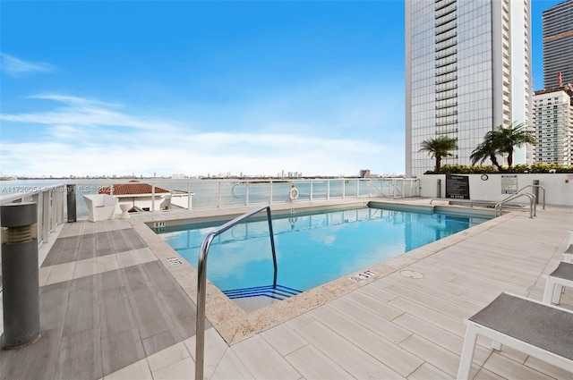 view of pool featuring a patio area and a water view