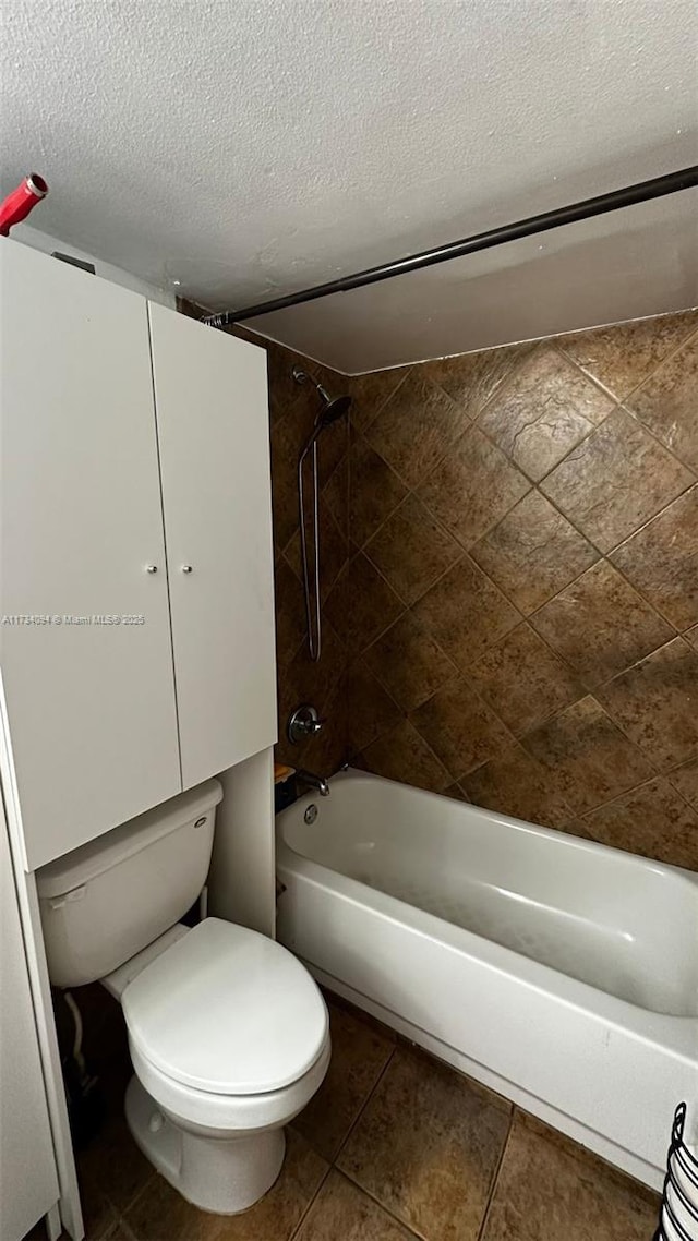 bathroom featuring toilet, tiled shower / bath combo, and a textured ceiling