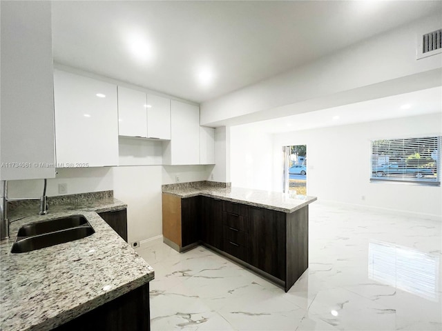 kitchen featuring white cabinetry, light stone countertops, sink, and dark brown cabinets