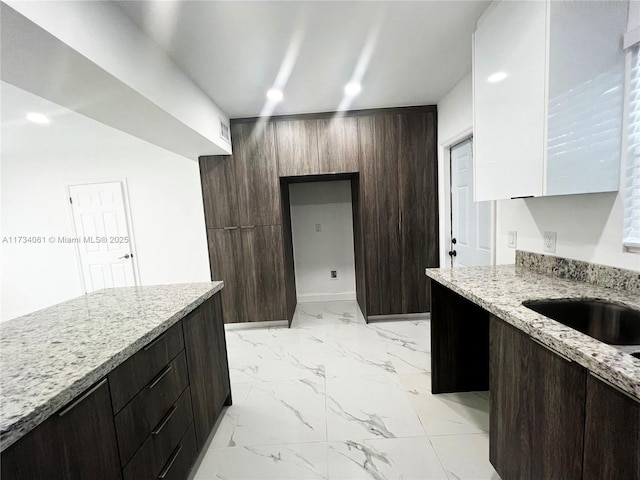 kitchen with dark brown cabinetry and light stone countertops