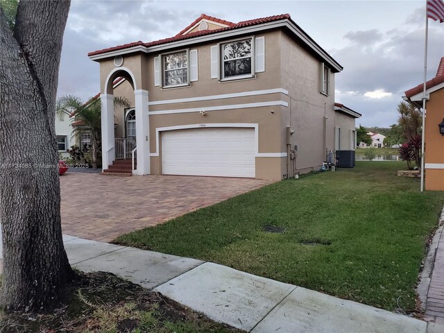 mediterranean / spanish-style house featuring central AC, a garage, and a front yard