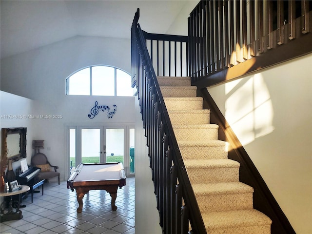 staircase featuring french doors, high vaulted ceiling, a healthy amount of sunlight, and tile patterned flooring