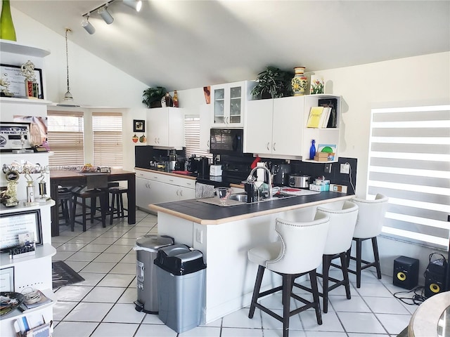 kitchen with sink, a breakfast bar area, black appliances, white cabinets, and kitchen peninsula