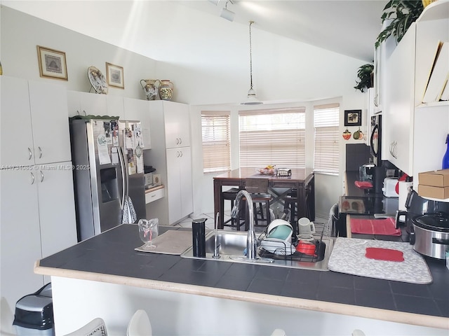 kitchen with white cabinetry, lofted ceiling, tile countertops, and stainless steel fridge with ice dispenser