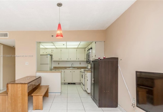 kitchen featuring pendant lighting, sink, white appliances, and light tile patterned flooring