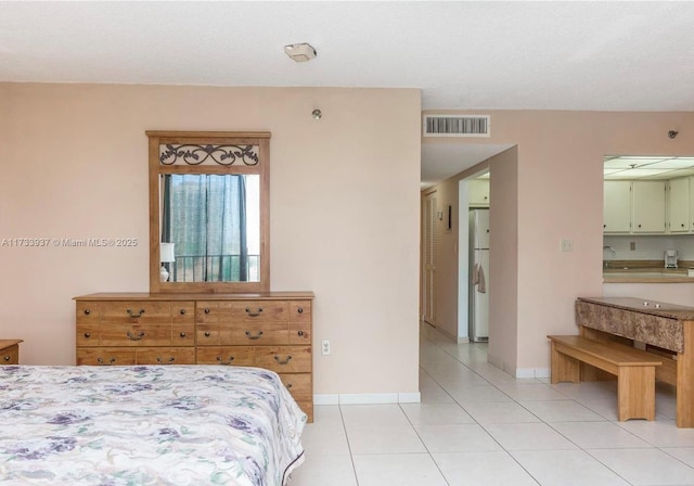 bedroom featuring light tile patterned flooring and white fridge