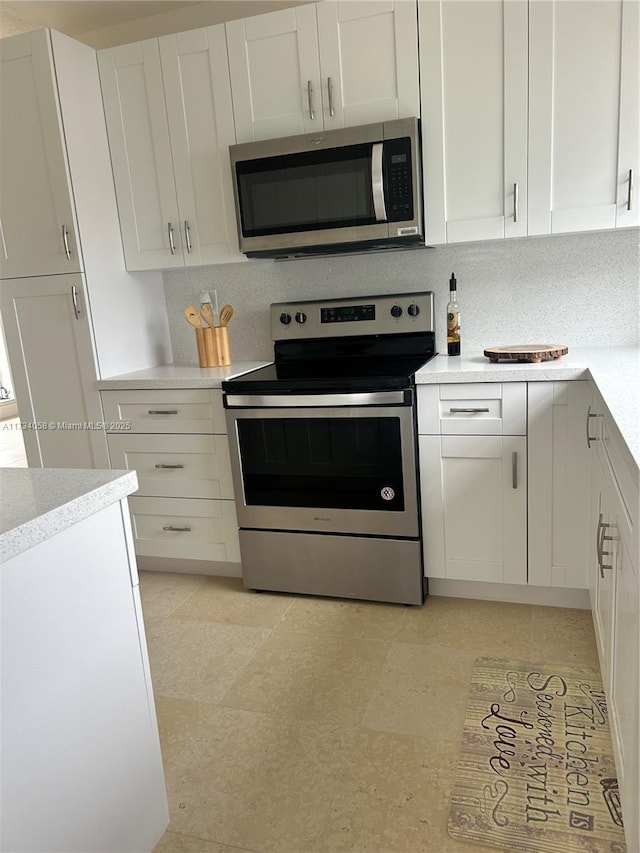 kitchen with tasteful backsplash, white cabinets, and appliances with stainless steel finishes